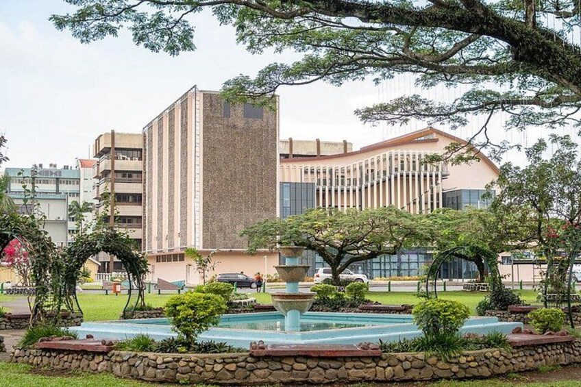 A building with a modern design, a fountain, and surrounding greenery. 4