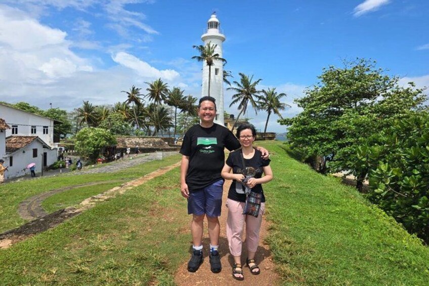A lighthouse, a grassy path, and palm trees. 3