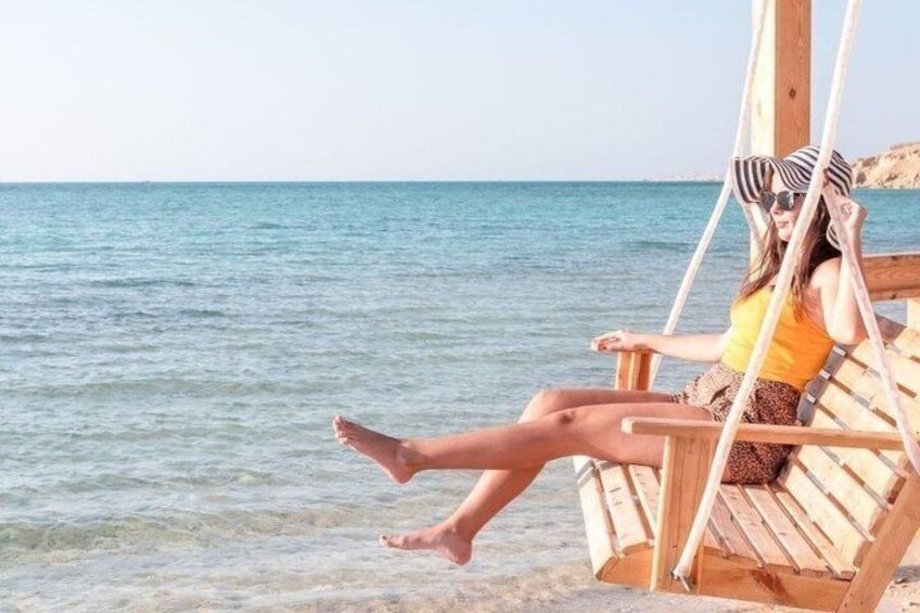 Une personne se détend sur une chaise longue en bois, au bord de la mer. 1