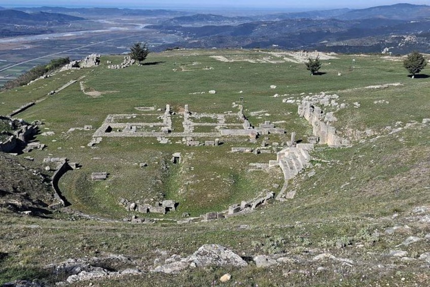 Un site archéologique ancien, avec des ruines situées sur une colline herbeuse. 1