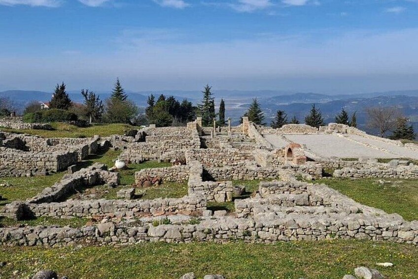 Des ruines antiques aux murs et aux allées en pierre, entourées d’arbres et surplombées par un ciel dégagé. 3