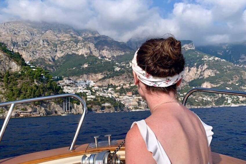 A person on a boat with a mountainous coastline in the background. 5