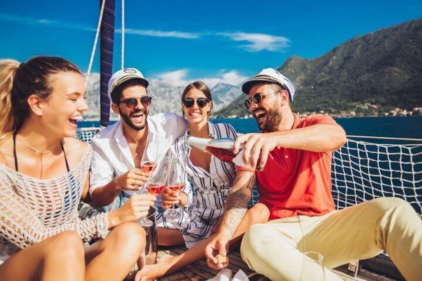 A group of people on a boat with drinks, surrounded by a mountainous landscape. 1