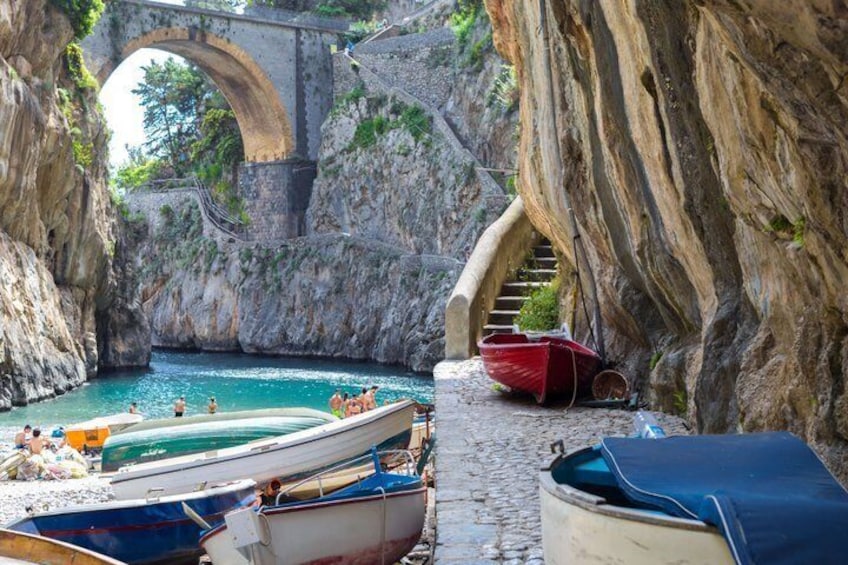 A rocky coastal area with boats docked, a stone bridge, and a staircase leading down to the water. 2