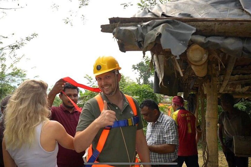 A person wearing a yellow hard hat and safety vest, interacting with another person. 1