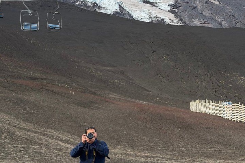 Iemand maakt een foto, een stoeltjeslift en een hek in een vulkaanlandschap. 4
