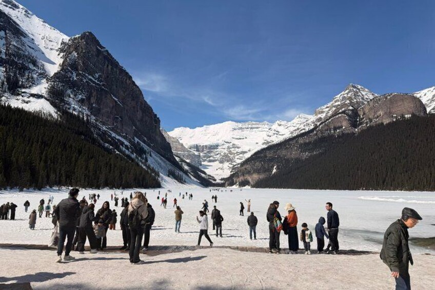 Eine Gruppe von Menschen auf einem schneebedeckten See, im Hintergrund Berge. 5