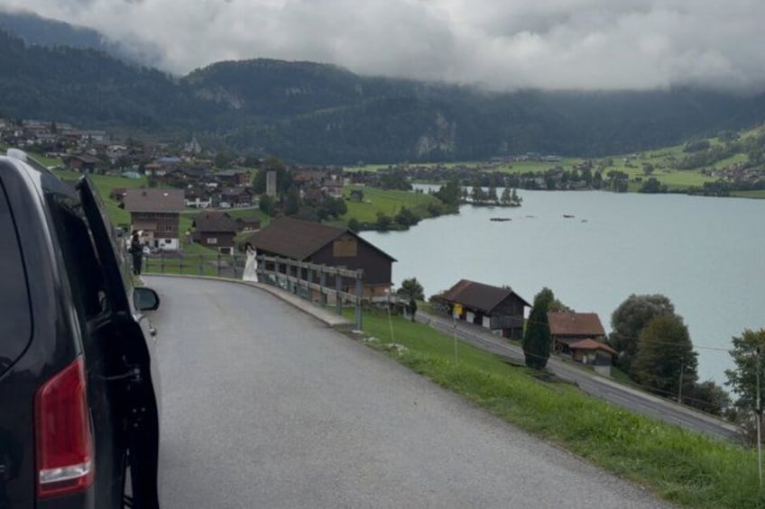 A road curving through a village with houses and a lake in the background. 3