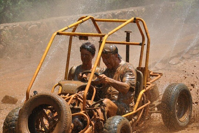 A person driving a yellow off-road vehicle through a dusty terrain. 5