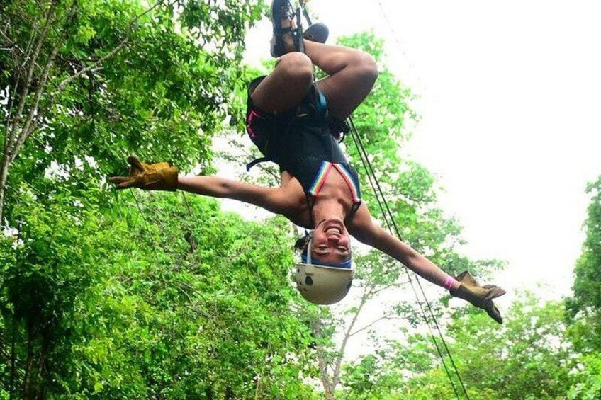 A person bungee jumping with a harness and helmet, surrounded by dense green foliage. 3