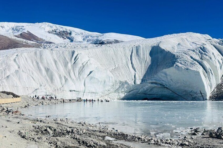 Un glaciar con una grieta, un lago helado y un grupo de personas observando. 1