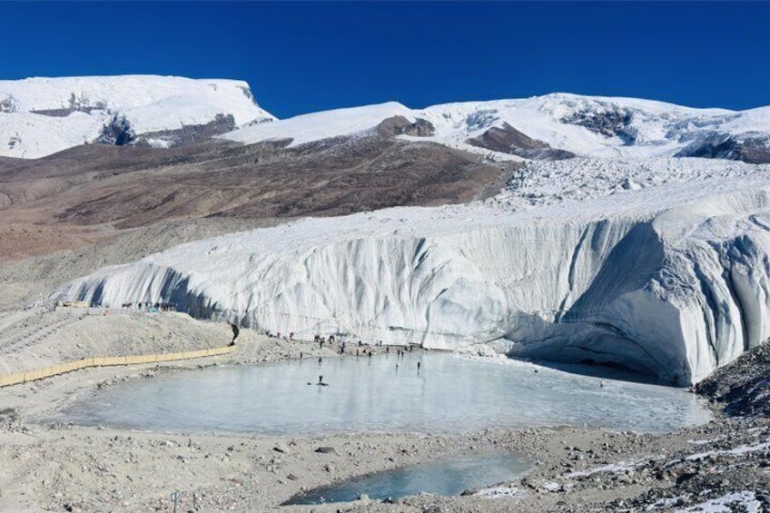 Un glaciar con un pequeño lago en su base, rodeado de montañas nevadas. 3