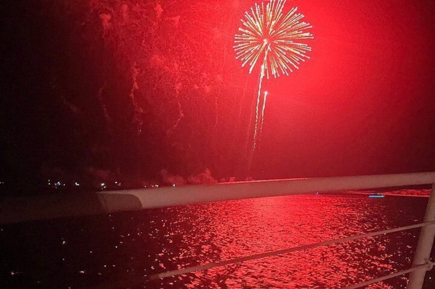 A nighttime scene with a large firework display over water, reflecting on the surface. 5
