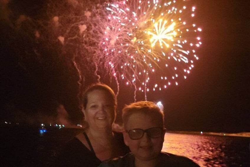 A person standing on a beach with fireworks in the background. 3