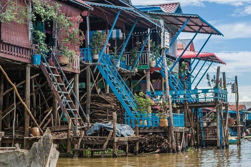 A traditional stilt house with blue railings and wooden stairs. 4
