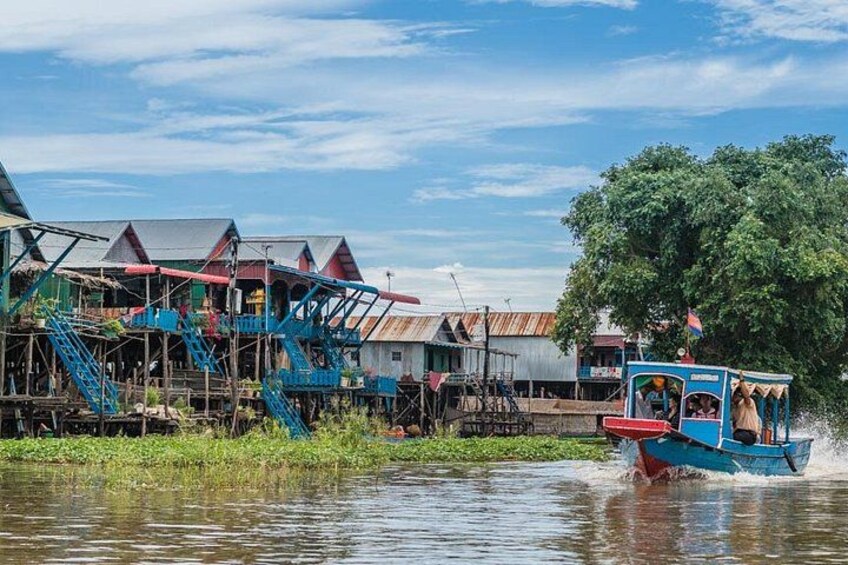 A blue boat with passengers, a wooden house with a staircase, and a tree. 1