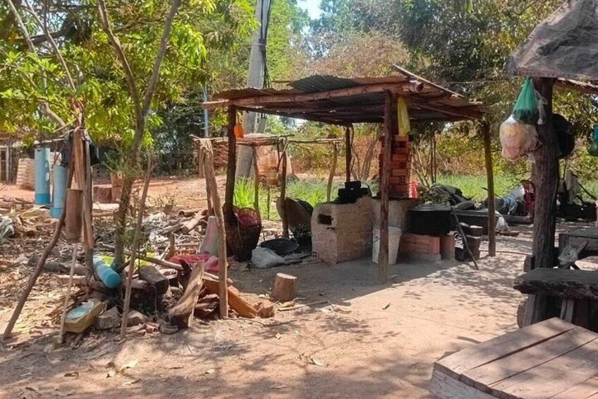 A rustic outdoor setting with a wooden structure, scattered debris, and various items like buckets and containers. 3
