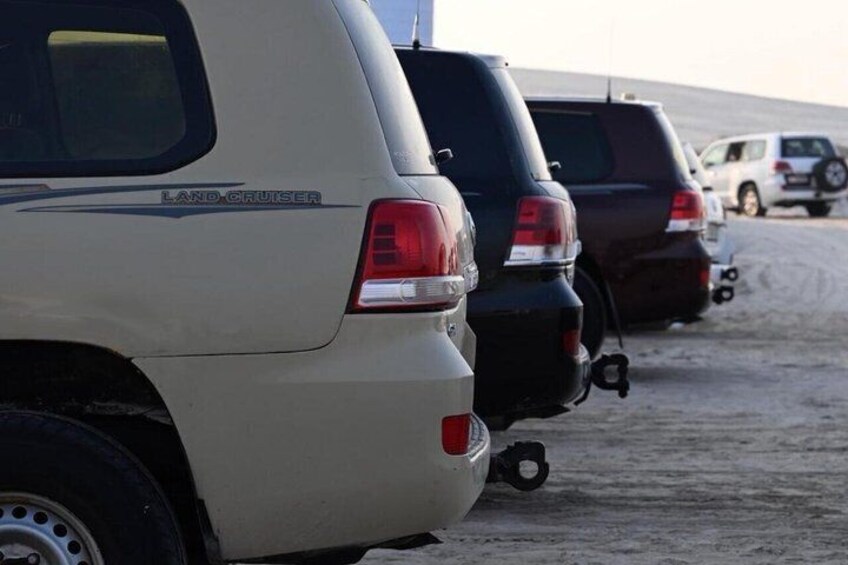 Una fila de SUVs estacionados, incluyendo un Land Cruiser color beige, en un estacionamiento. 5