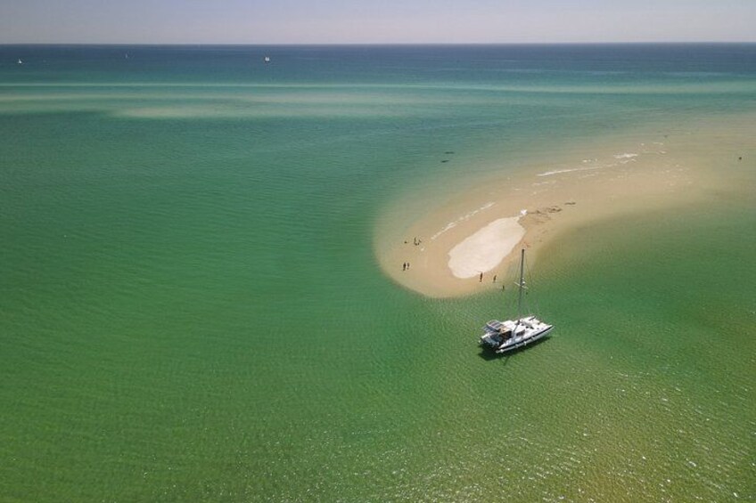 Un mar turquesa cristalino, una playa de arena y un velero. 1