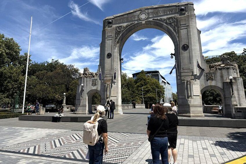 A large stone archway with inscriptions, surrounded by a paved area with patterned tiles. 1