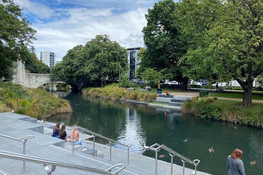 A riverside park with a bridge, trees, and people sitting on a dock. 3