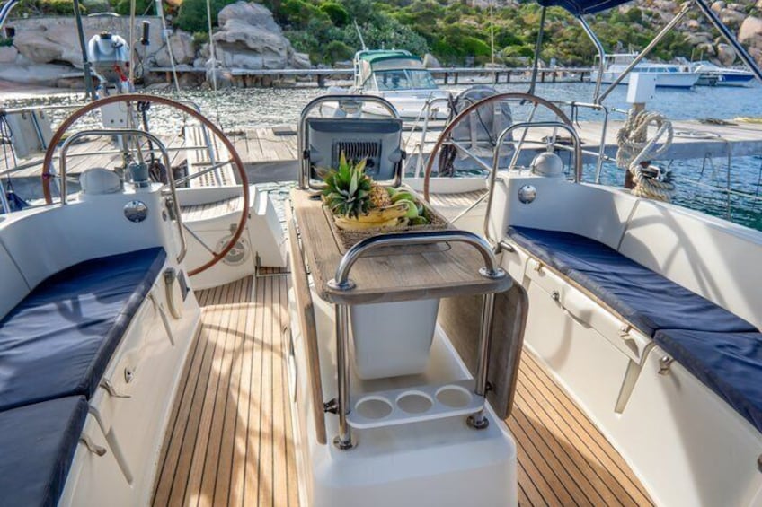 A boat deck with seating, a small table with a plant, and a view of the marina and rocky shoreline. 4