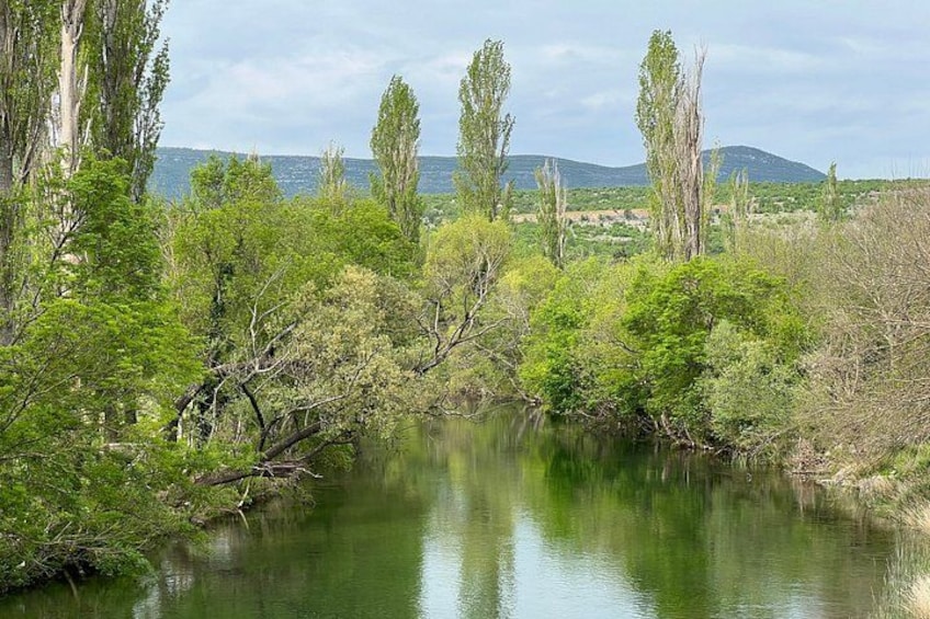 A calm river with trees and hills in the background. 2