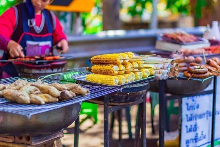 A street food vendor grilling corn on the cob and other meats. 1