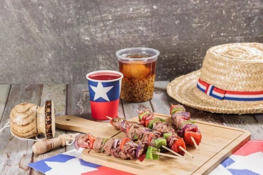 Skewers of meat and vegetables, a straw hat, a cup with a star, and a jar of pickles on a wooden surface. 3