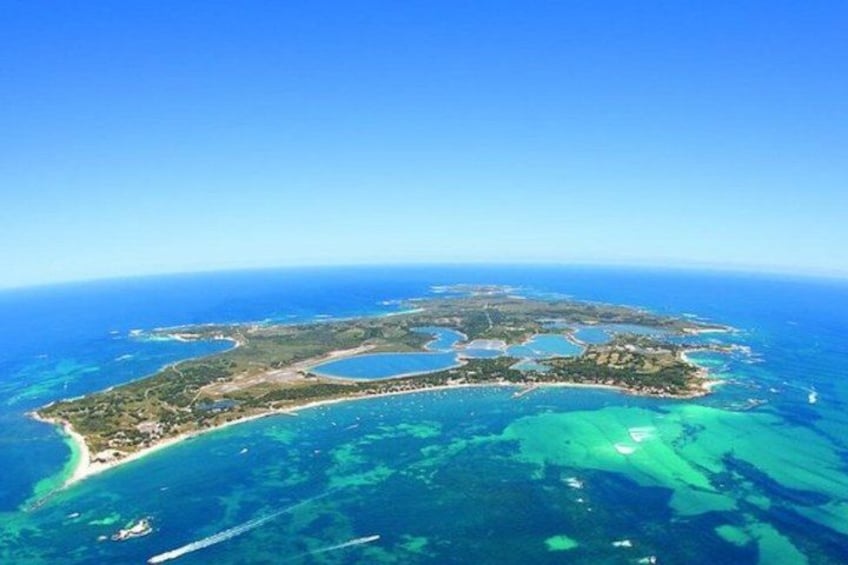 An aerial view of a coastal island with clear blue waters, a sandy beach, and a small bay. 3