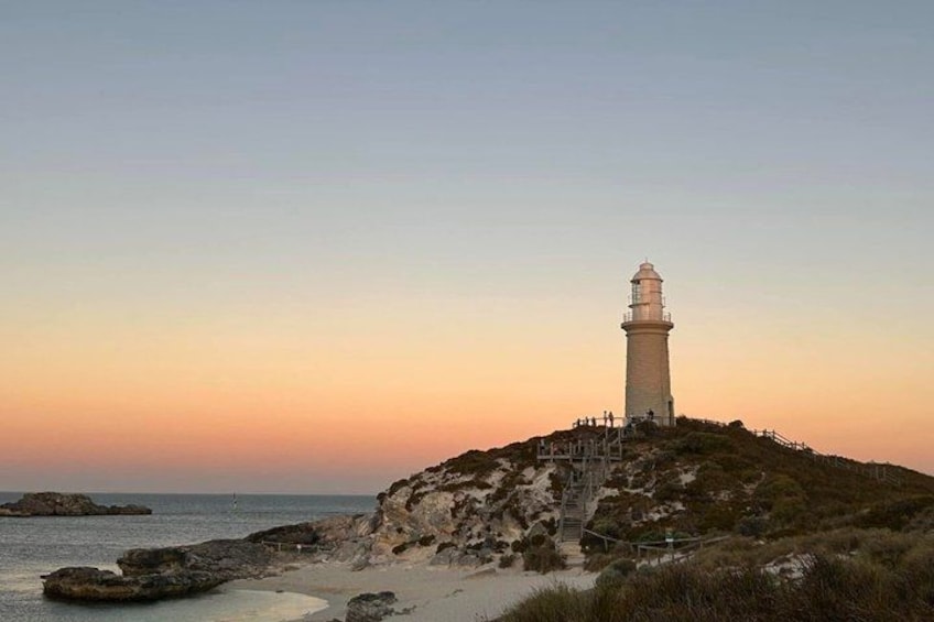 A lighthouse on a rocky outcrop by the sea during sunset. 2