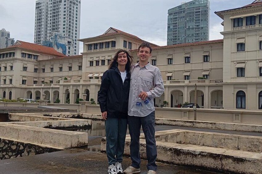 Two people standing in front of a historic building with arched windows and a stone facade. 2