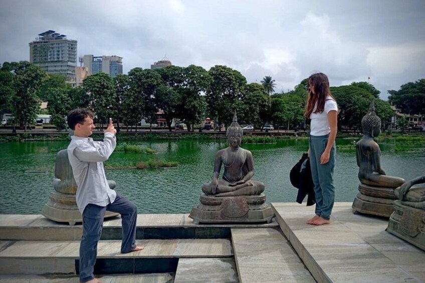 Una persona scatta una foto a una statua raffigurante una figura seduta in un parco, sullo sfondo si vedono acqua e alberi. 4