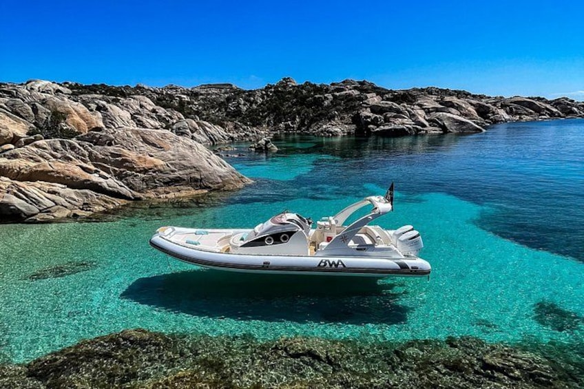 A boat named 'GWA' on clear turquoise water with rocky terrain in the background. 2