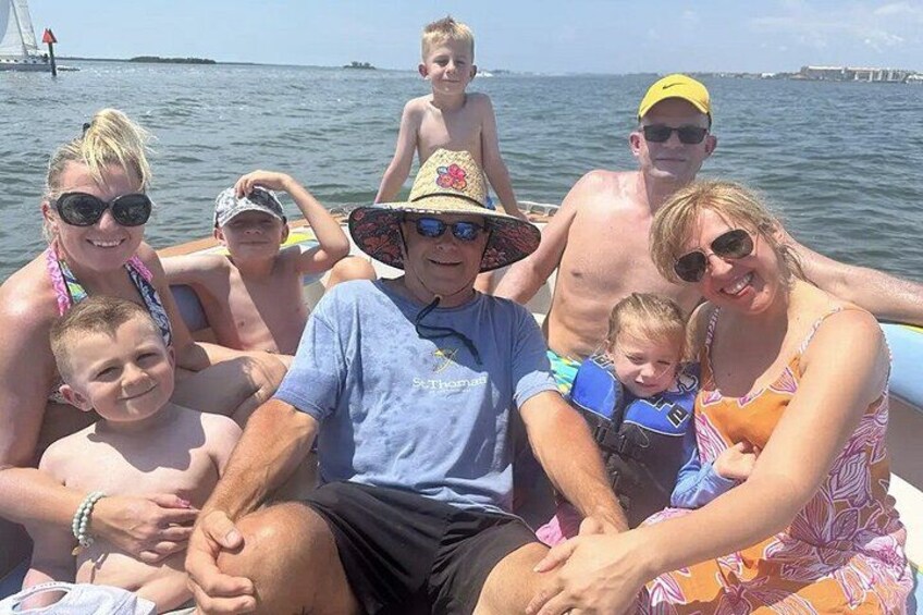 Eine Gruppe von Menschen auf einem Boot, mit einem Gewässer und einem entfernten Steg im Hintergrund. 5
