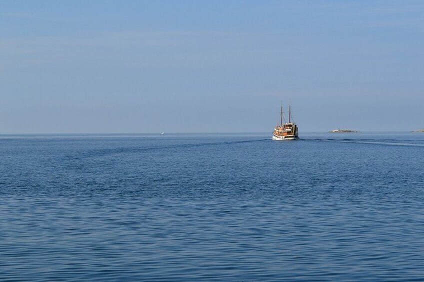 A calm sea with a single boat in the distance and a small island. 2