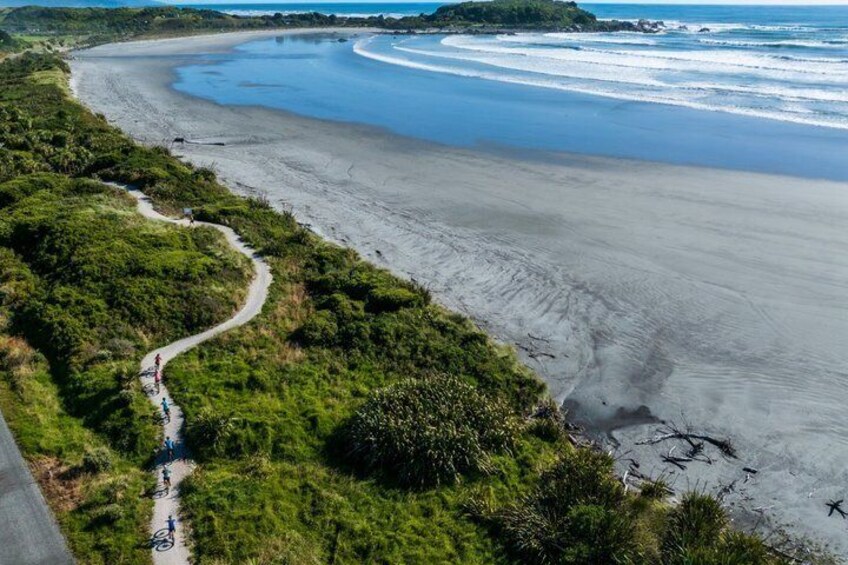 A coastal landscape with a winding path, sandy beach, and ocean waves. 1