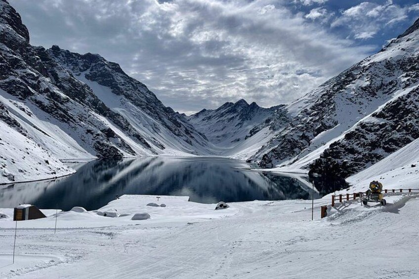 Un col de montagne enneigé, avec un pont enjambant une rivière, le tout entouré de sommets couverts de neige. 3