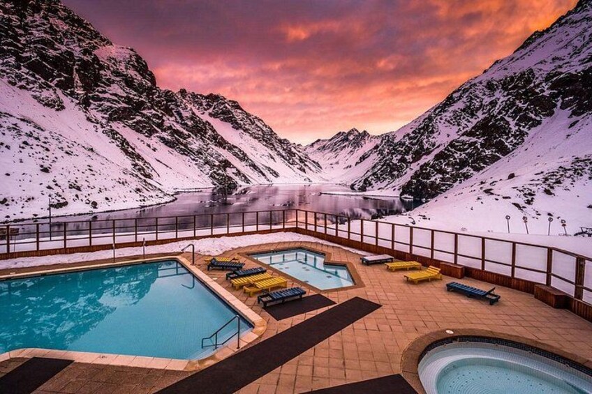 Un espace piscine avec des chaises longues, entouré de montagnes enneigées et surplombé d’un ciel dégagé. 5