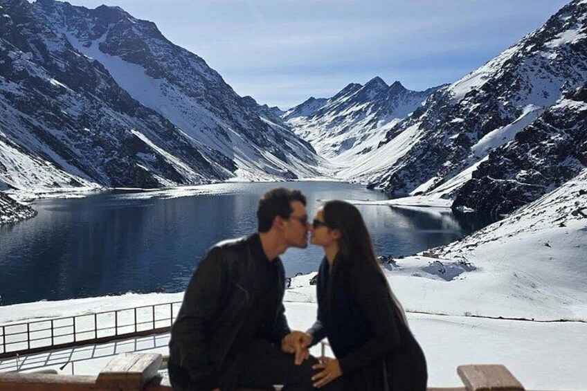 Un couple est assis au bord d’un lac, avec des montagnes enneigées en arrière-plan. 4