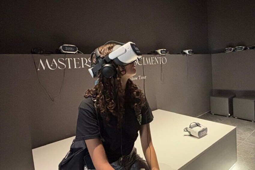 A person wearing a VR headset in a room with a display case labeled "MASTERS" and "Slow Tour." 1