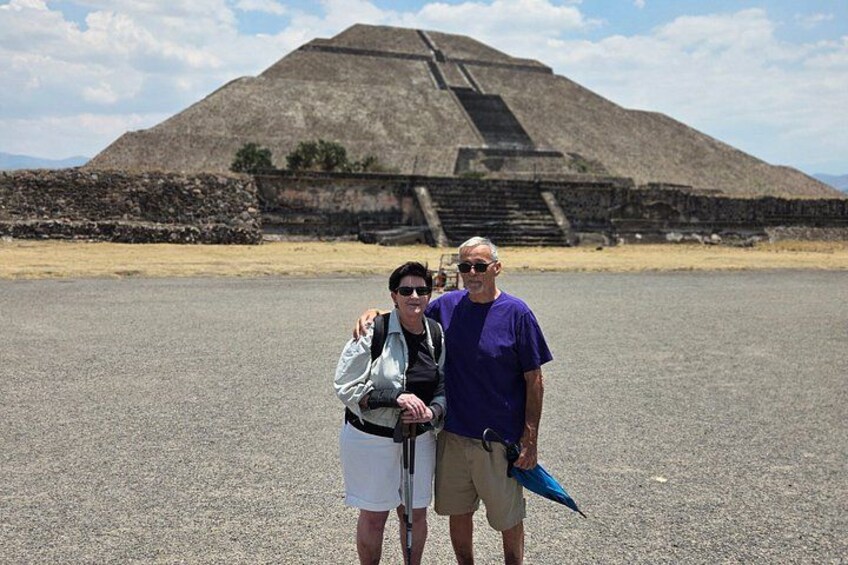 Due persone in piedi di fronte a una grande piramide con una scala che conduce in cima. 5
