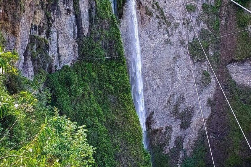 A waterfall cascading down a rocky cliff surrounded by lush greenery. 5
