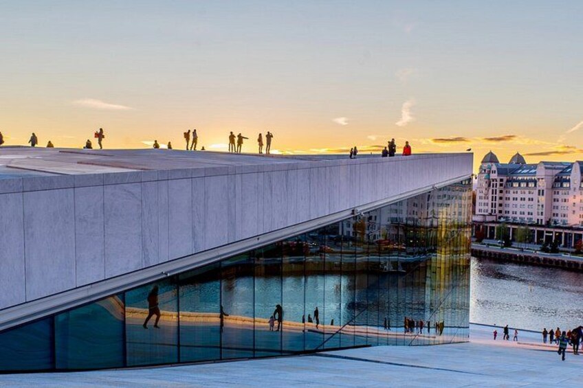 A modern architectural structure with a glass facade, a waterfront, and a sunset in the background. 3