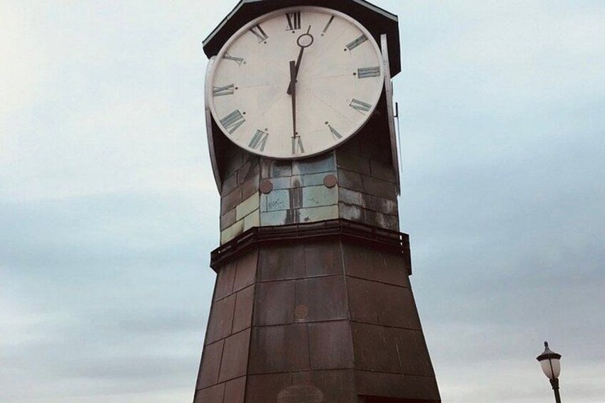 A clock tower with Roman numerals and a street lamp. 5
