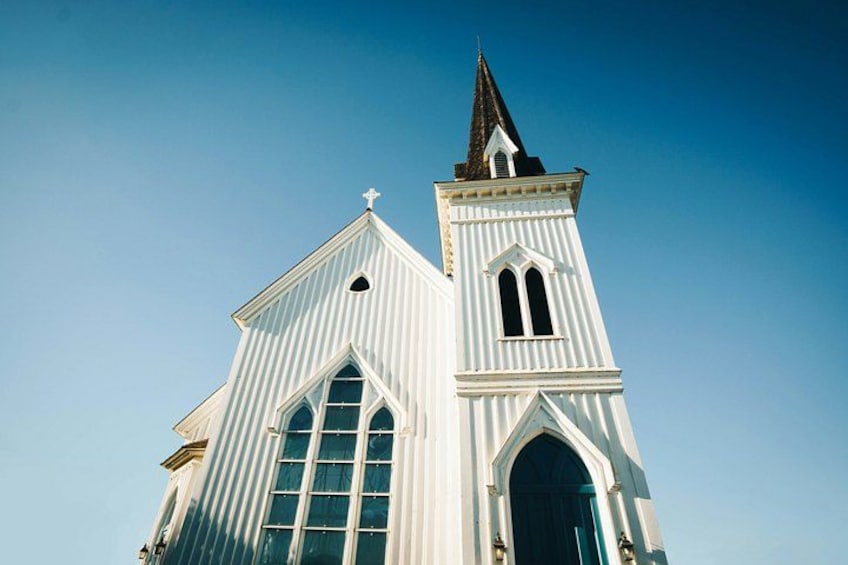 Una iglesia blanca con un campanario alto y una cruz en la parte superior. 2