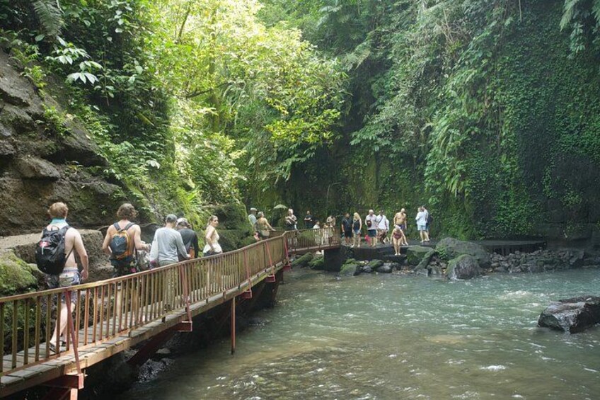 Een houten brug over een rivier, omgeven door weelderige begroeiing. 3