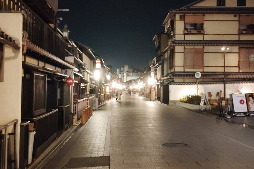 Une rue de nuit, bordée de bâtiments traditionnels, éclairée par des lampadaires, et sous un ciel dégagé. 5