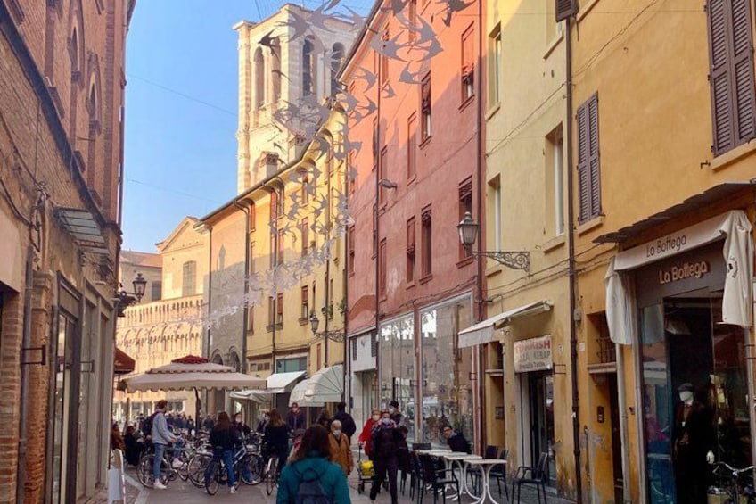 A narrow street with buildings, bicycles, and people. 4
