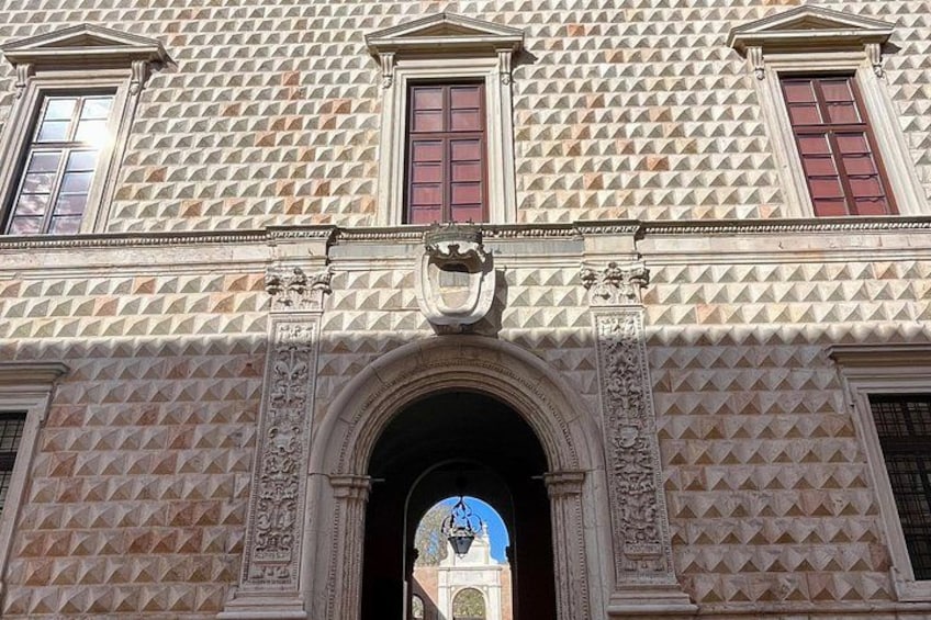 En bygningsfacade med et geometrisk mønster, en buet indgang og dekorative søjler. 2